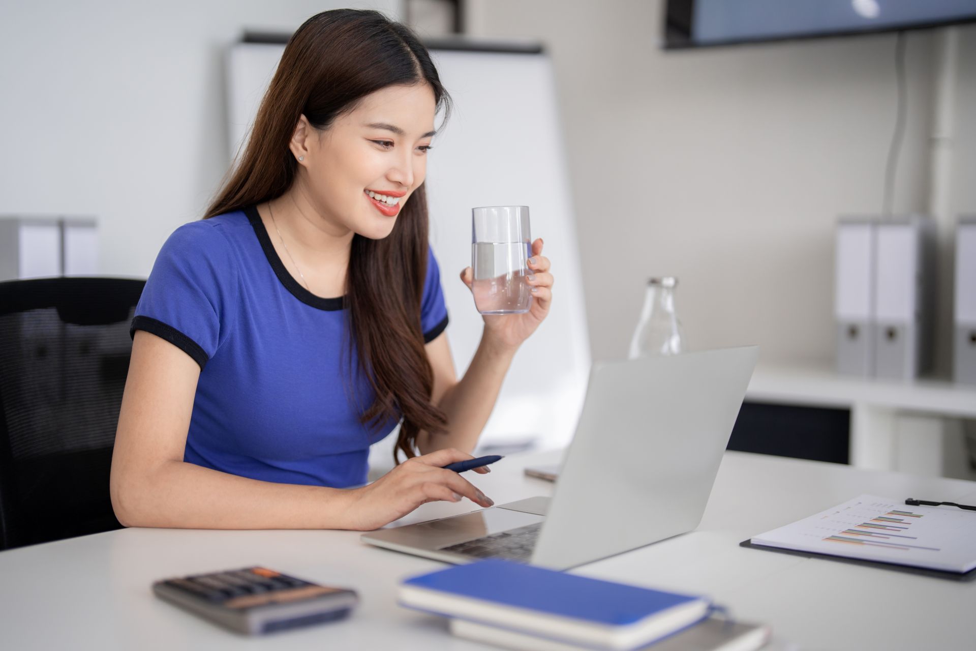 Person working comfortably at a laptop with a glass of water, representing a calm creative space that an onlyfans agency often encourages for enjoyment.
